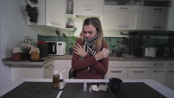 Solunum hastalığı, boğazı ağrıyan yetişkin bir kız, rahatsızlanıyor ve mutfakta otururken boğazı ağrıdığı için ilaç alıyor. — Stok video