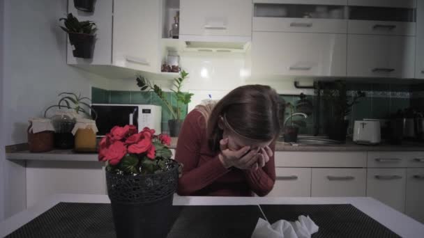 Mujer joven que sufre de una enfermedad respiratoria alérgica a las plantas de la casa con flores, estornudos y toallitas con pañuelo en la cocina — Vídeo de stock