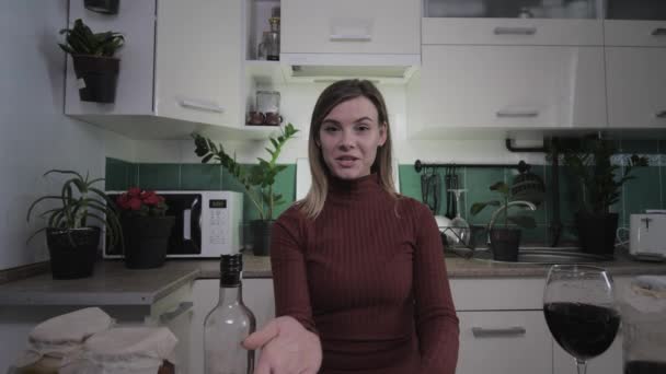 Młoda atrakcyjna gospodyni domowa pisze recepty wideo w kuchni w domu na swoim blogu i podnosi szklankę wina, żeński vlog — Wideo stockowe