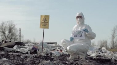 Biyolojik Tehlike Acil Servisi, Tehlikeli Madde Biyologunun Koruyucu Kostüme dönüşümü, işaretin yeşil geri dönüşüm olduğunu gösteriyor.