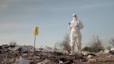 Biyolojik tehlike, koruyucu giysilere bürünmüş tehlikeli madde adamı işaretler gösteriyor. Gezegeni çöplükten kurtarıyor.