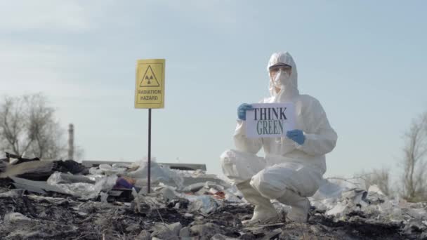 방호복을 입은 잠꾸러기 생물학자는 공기중에 포인터 방사선 위험 이 있는 그린 이 폐차장에 있다고 생각하는 표지판을 보여 주고 있다. — 비디오
