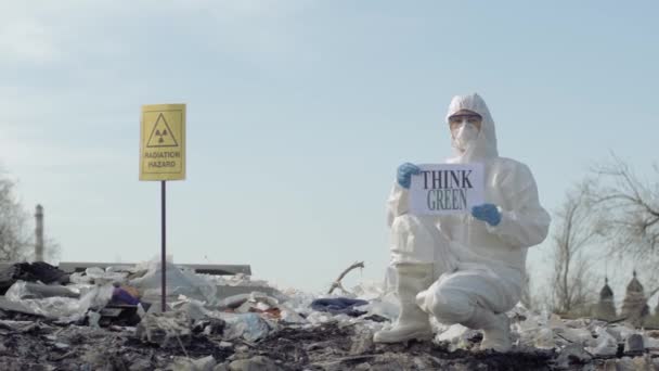 Hazmat pessoa em Traje de proteção mostra sinal pensar verde em lixeira com perigo de radiação ponteiro ao ar livre — Vídeo de Stock