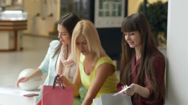 Neşeli alışveriş düşkünleri cep telefonuyla fotoğraf çekilirken, satış sezonunda ellerinde paketler ve Kara Cuma indirimleriyle alışverişe çıkıyorlar.