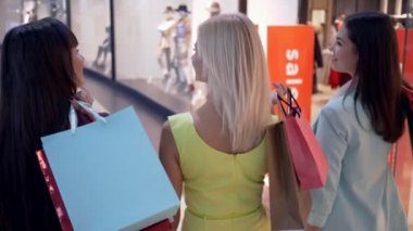 Alış veriş delisi kızlar indirim ve satış sezonunda moda mağazalarını satın alırken alışveriş merkezlerinde dolaşıyorlar.