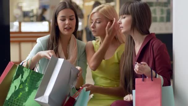 Happy girlfriends at shopping discuss new purchases in packages from expensive boutiques in season of sales and discounts — Stock Video