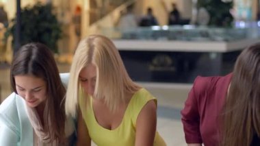 Alışverişkolik kadın arkadaşları, Kara Cuma satışları ve indirimlerindeki pahalı moda butiklerinde alışveriş çantalarıyla cep telefonlarında fotoğraflanıyorlar.