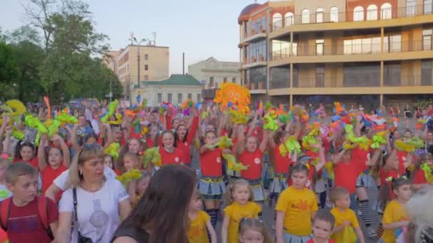 Fête d'été de vacances, de nombreux enfants et adolescents en vêtements lumineux agitant les mains et criant des chants dans la rue de la ville — Video