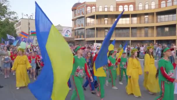 Festivalde ellerinde bayraklar olan yetişkinler ve çocuklar şehir caddesinde yürüyor. — Stok video