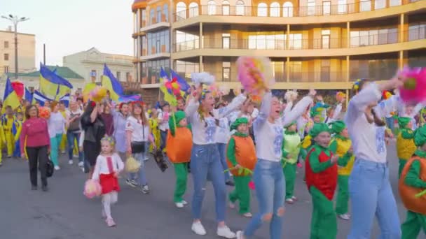 Farklı etnik kostümlü kalabalık ellerinde bayraklarla şehir caddesinde yürüyor, ilahi söylüyor ve açık havada el sallıyor. — Stok video