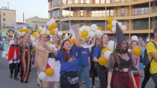 Feste, giovani folla in costumi diversi con palloncini camminare lungo la strada della città e gridare canti all'aria aperta — Video Stock