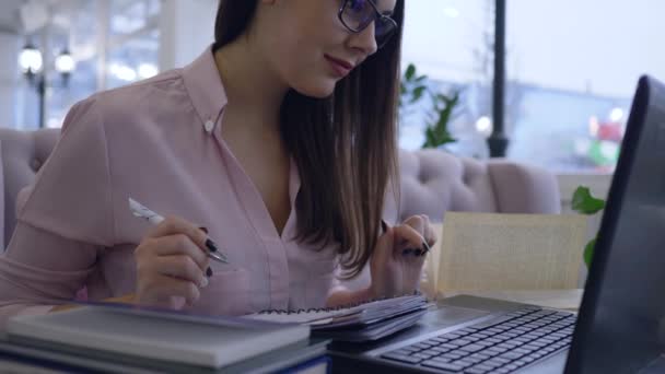 Távoktatás, boldog diák lány dolgozik laptop és könyvek jegyzetel notebook közeli ülő asztalnál — Stock videók