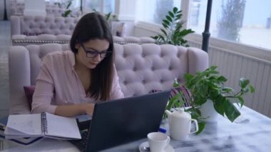 Uzaktan eğitim veren modern bilgisayar teknolojisi, bilgisayarla çalışan mutlu öğrenci kız çevrimiçi dersler almak ve not defterine not almak için çalışıyor.