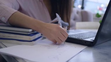 Çevrimiçi kurslar, zeki öğrenci kadın video dersinden ders çalışmak ve not defterine yakın çekim notlar almak için modern bilgisayar teknolojisini kullanıyor.