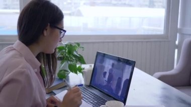 Çevrimiçi ders, gözlüklü kadın öğrenciler kendi kendilerini geliştirmeyi öğreniyorlar modern teknolojiyi eğitimde kullanıyorlar ve not defterine notlar alıyorlar.