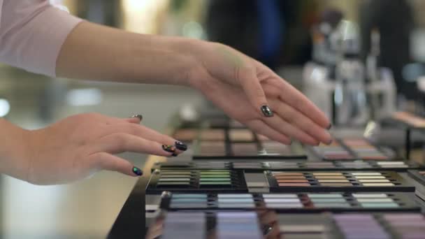 Compra de cosméticos, comprador hembra seleccionar sombra de ojos de la paleta de diferentes colores para el maquillaje vívido y aplicar pruebas de cosméticos en la mano en la tienda — Vídeos de Stock