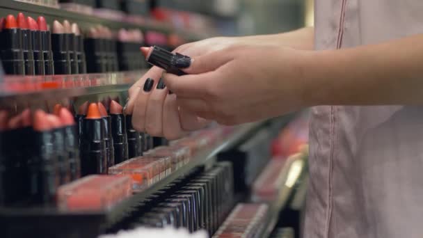 Mujer cliente elige nuevo brillo de labios para el maquillaje profesional y aplicar pruebas de cosméticos en la mano en la tienda — Vídeo de stock