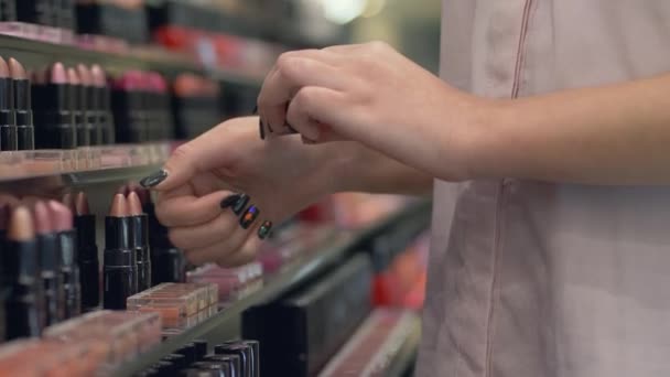 Cosméticos decorativos de las mujeres, hembra de moda elige lápiz labial para el maquillaje brillante y aplicar pruebas de cosméticos en la mano en la tienda — Vídeo de stock