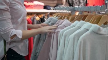 Moda alışverişi, kadın eli mevsimlik indirimler sırasında mağazadaki askılardan şık yeni kıyafetler seçiyor ve kendimi deniyorum.