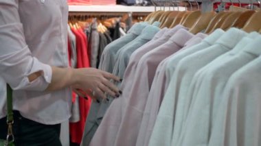 Alışverişte mutlu bir kız, genç müşteriler mağazada sezonluk indirimler sırasında moda mağazasında yeni kıyafetler seçiyor.