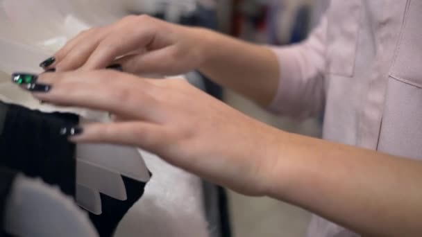 Ruce nakupující žena vybírá nové stylové oblečení na ramínka v módním butiku během prodejní sezóny, nesoustředěné pozadí — Stock video
