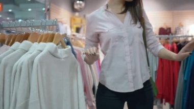 Alışveriş satışları, çekici bir kadın mağazada indirimler sırasında aynanın önünde yeni kıyafetler seçiyor ve deniyor.