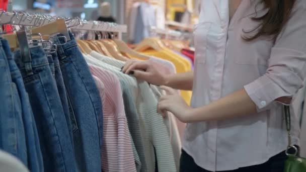 Bezoek van de winkel, mooie shopaholic vrouw kiest nieuwe kleren in de modewinkel tijdens kortingen in het winkelcentrum — Stockvideo