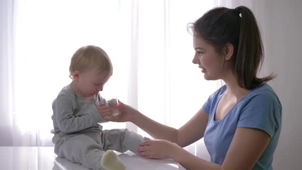Oltja a szomjúságot a kisgyermek, síró kisfiú iszik tiszta vizet az üvegből az anya kezét oltani szomjúság természetes fényben — Stock videók