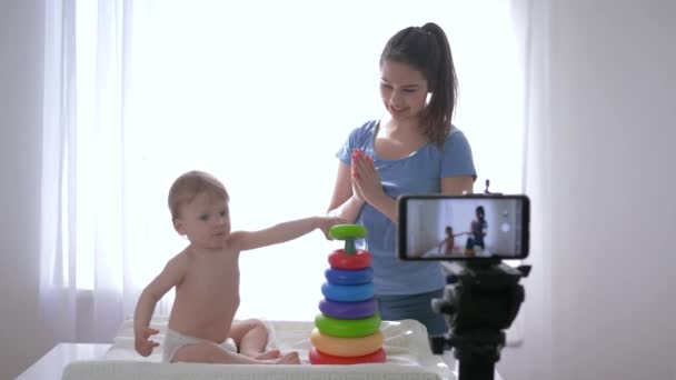 Видеоблог, мальчик с женщиной, играемый образовательными игрушками и запись видео в социальных сетях в прямом эфире на мобильный телефон для абонентов в социальных сетях — стоковое видео