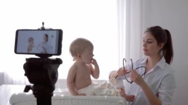 İnternet araştırması, steteskoplu doktor kadın takipçiler için akıllı telefondan canlı yayınlanan eğitim videosunda ağlayan çocuğun kalp atışlarını ve nefesini kontrol ediyor.