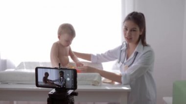 Çevrimiçi eğitim, ünlü vlogger kızı doktor canlı yayında yürümekte olan çocuğun tıbbi muayenesi sırasında cep telefonuyla sosyal medya videosu kaydediyor.