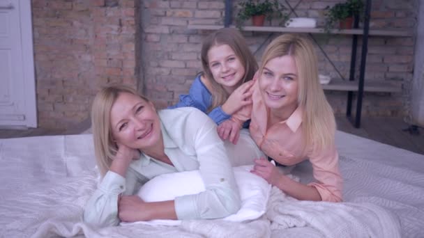 Rodinný volný čas s matkou, šťastná maminka si užívá relaxaci s krásnými dcerami ležícími na posteli při odpočinku doma — Stock video