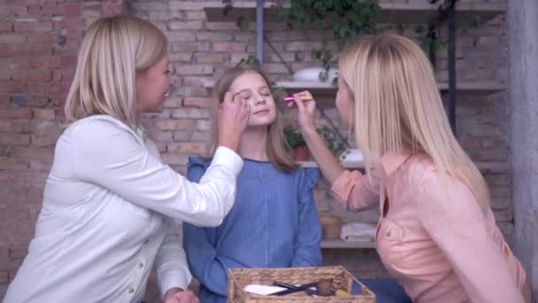 Maquillaje en casa, mamá divertida con hija adulta poner cosméticos en la cara de la niña y tontear durante la diversión sentado en la cama — Vídeos de Stock