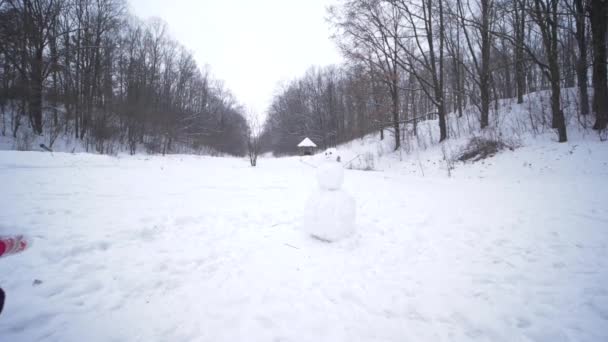 Bambina scolpisce un pupazzo di neve durante una nevicata durante le vacanze invernali — Video Stock