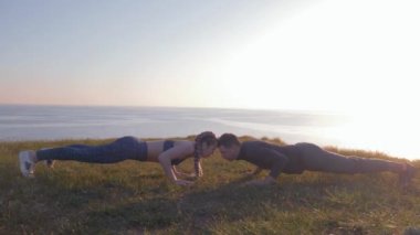 Açık hava egzersizi, birbirine aşık spor çiftleri gün batımında dağda güzel bir manzaraya karşı şınav çekiyorlar.
