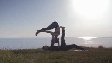 Sağlık yaşam tarzı, yoga çifti çayırlarda egzersiz yapıyor doğanın tadını çıkarıyor, denizin arka planında temiz hava