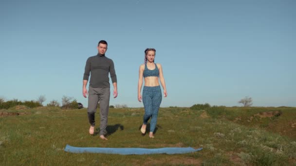 Hälsosam livsstil, par slappnar av innan träning i frisk luft när du står på sportmatta hålla händerna på bakgrunden av himlen med fåglar — Stockvideo