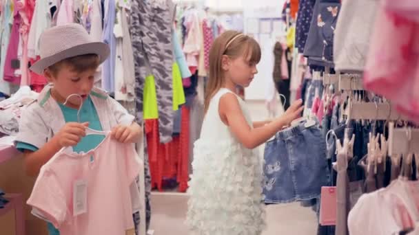 Niños en las compras, pequeños compradores eligen nueva ropa de moda en la boutique caro — Vídeos de Stock