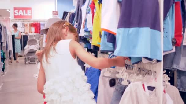 Модные магазины, дети клиенты выбирают новую стильную одежду в магазине — стоковое видео