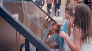 Kendi servisinde yeni teknolojiler, kız arkadaşı olan çocuk modern alışveriş merkezinin yeri hakkında bilgi edinmek için dokunmatik büfeler kullanıyor.