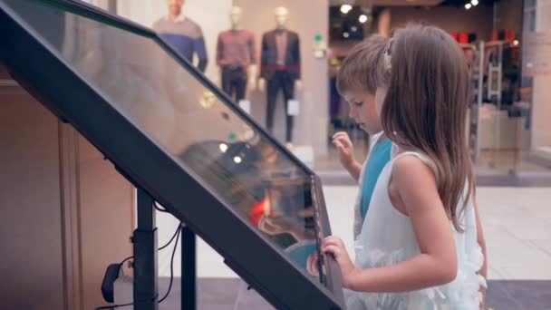 Los niños modernos utilizan el panel interactivo mientras que hacen una compra en línea en el centro comercial — Vídeo de stock