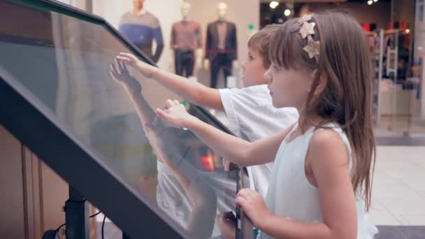Self-service στο εμπορικό κέντρο, σύγχρονο παιδί αγόρι και κορίτσι χρησιμοποιεί Πληροφοριακό σύστημα για τη θέση αναζήτησης της μπουτίκ — Αρχείο Βίντεο