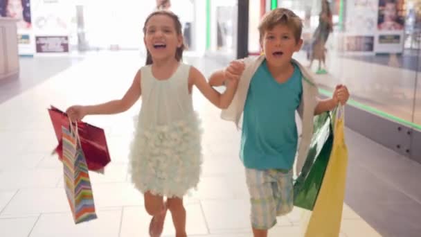 在黑色星期五的促销活动中，快乐的孩子们提着购物袋跑去打折购物 — 图库视频影像