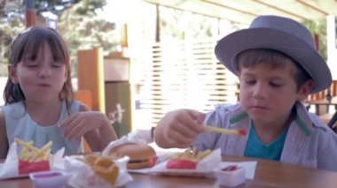 Paket yemek, mutlu arkadaşlar soslu patates kızartması ve hamburger yiyen çocuklar öğle yemeği sırasında sokak kafede.