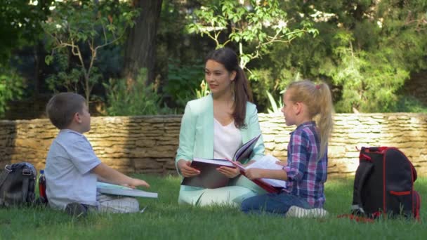 Lektion über die Natur, intelligente Schüler Jungen und Mädchen mit Lehrerin weiblich Bücher lesen und plaudern während des Unterrichts — Stockvideo