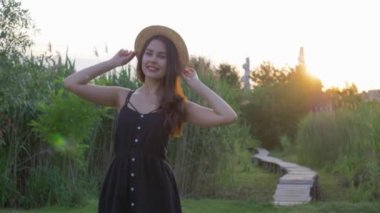 Hasır şapkalı mutlu gülümseyen kızın portresi yeşil çimenlerin arasında.