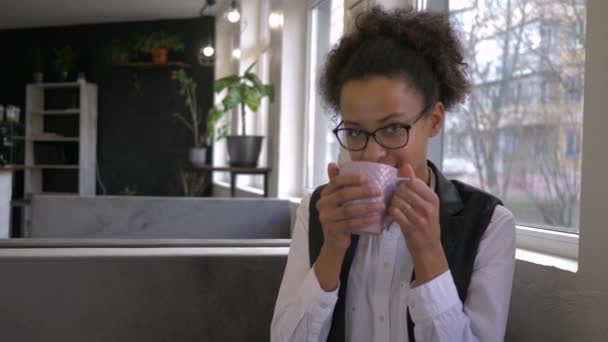 Kaffe paus av glad svart tonåring flicka i glasögon med kopp varm dryck närbild på café på fritiden — Stockvideo