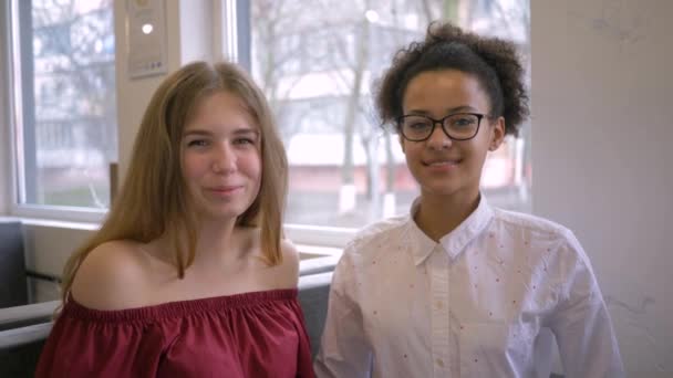 Multiethnische Beziehung, fröhliches afrikanisch-amerikanisches Teenie-Mädchen umarmt Freundin und lächelt im Café — Stockvideo