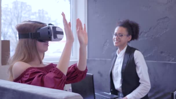 Майбутнє зараз, радісні міжнародні друзі дівчина використовує VR-маску і сучасні технології ноутбуків для гри віртуальної реальності, сидячи в кафе — стокове відео