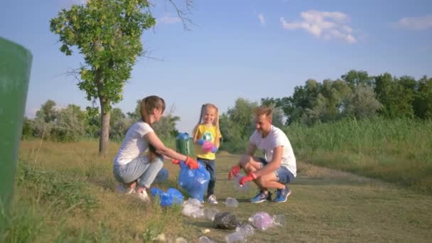 Problém znečištění plastů, mladá rodina s dívkou se stará o ekologii přírody a sbírat polyethylenové odpadky v pytli na odpadky při čištění od znečištění — Stock video